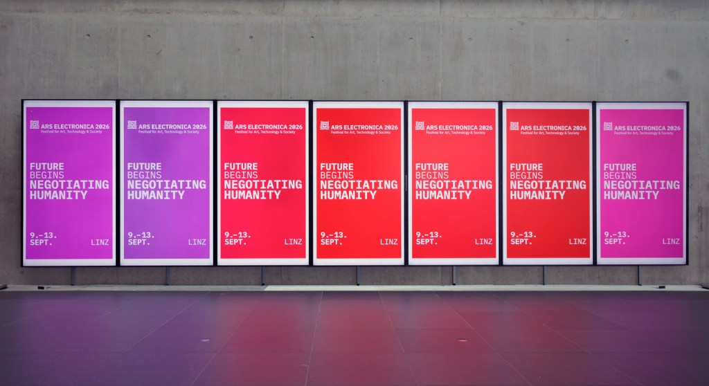 A series of digital displays on a concrete wall showcasing advertisements for Ars Electronica 2026, featuring the slogan 'Future Begins Negotiating Humanity.' The displays are visually distinguished by varying colors and include event dates (September 9-13) and location (Linz).